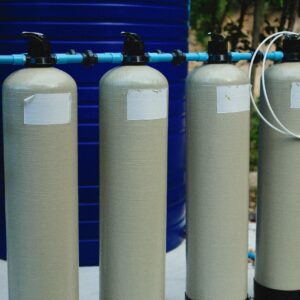 Photo by Alexey Demidov Four beige tanks in an outdoor water treatment setup with blue piping.